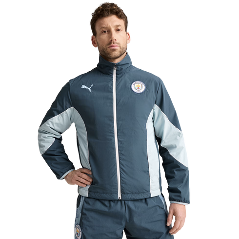 A man wearing a blue and light-blue Puma track suit featuring the Manchester City F.C. crest.