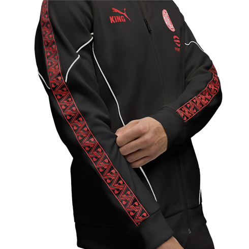 A person wearing a black Puma AC Milan track jacket with red patterned sleeve stripes, white piping, and red team logos against a white background.