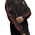 A person wearing a black Puma AC Milan track jacket with red patterned sleeve stripes, white piping, and red team logos against a white background.