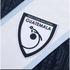 Close-up of the Guatemala national team crest on a white and blue jersey, featuring a stylized quetzal logo and the words "SELECCIÓN NACIONAL GUATEMALA."