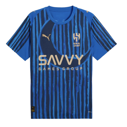 A blue Al-Hilal football jersey by Puma with vertical stripes, a large crescent motif, and the Savvy Games Group sponsor logo in gold.