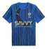 A blue Al-Hilal football jersey by Puma with vertical stripes, a large crescent motif, and the Savvy Games Group sponsor logo in gold.