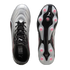 Top and bottom views of a Puma soccer cleat with a silver and black gradient upper and pink studs on its soleplate, set against a black background.