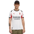 A man wearing a white Puma AC Milan soccer jersey with red accents, a black cap, and olive green pants against a black background.