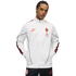 A man wearing a white Puma KING track jacket with red accents and black AC Milan pants against a black background.