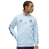 A man wearing a light blue Manchester City track jacket with the team crest, PUMA King logo, and patterned sleeve tape.