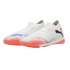 A pair of Puma turf soccer shoes in white, featuring pink and blue gradient designs and a bright coral pink lugged sole, isolated against a black background.