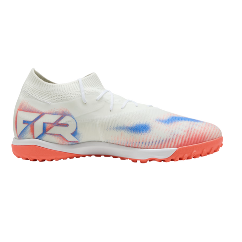 White turf soccer shoe with red and blue graphics, "FTR" branding on the heel, and a red-orange studded outsole. Shown from a side profile against a black background.