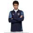 A young man with arms crossed wearing a navy Puma jacket with light blue patterned sleeves and a team crest, set against a black background.