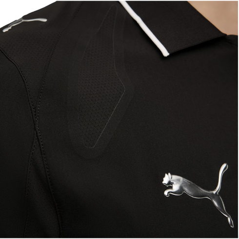 Close-up of black athletic wear with a metallic silver Puma logo. The garment features a textured mesh panel and a black collar with thin white trim.