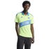 A smiling man wearing a neon yellow Charlotte FC polo shirt and black cargo pants against a black background.