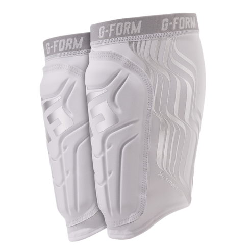 White G-FORM shin guard sleeves with silver contoured padding and grey elastic bands, shown against a black background.
