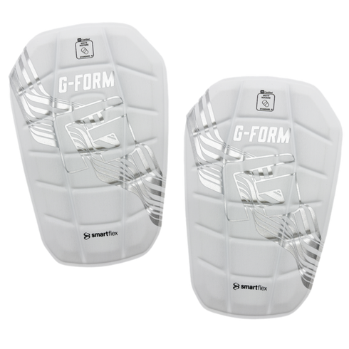 A pair of white G-FORM soccer shin guards with silver metallic graphics and SmartFlex branding.
