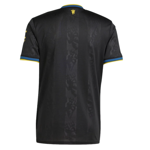 Back view of a black Manchester United football jersey with subtle vertical stripes, embossed tonal devil patterns, and yellow and blue trim on the collar and sleeve cuffs.