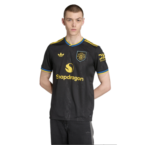 A man wearing a black Manchester United soccer jersey with yellow and blue accents and the Snapdragon logo, against a black background.