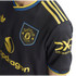 Close-up of a black and yellow Manchester United soccer jersey with the club crest, Snapdragon sponsor logo, and Adidas Trefoil logo.