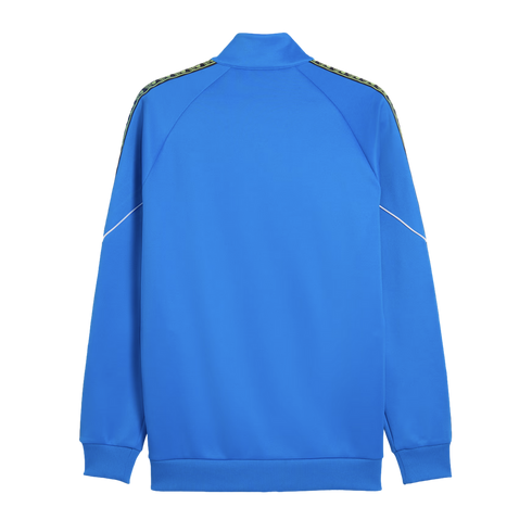 Back view of a blue track jacket featuring patterned shoulder tape, thin white sleeve accents, and ribbed trim, shown against a black background.