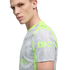A fair-skinned man with blond hair wears a grey and lime green Puma sports jersey featuring a water droplet pattern and sponsorship branding.
