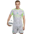 Man in a Manchester City soccer kit, grey with neon green accents, holding a soccer ball under his arm against a black background.