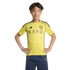 A young Asian male wearing a yellow Al-Nassr football jersey stands with hands on his hips against a black background.