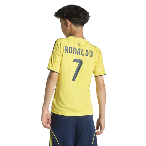 Back view of a boy in a yellow "RONALDO 7" soccer jersey and navy shorts against a black background.