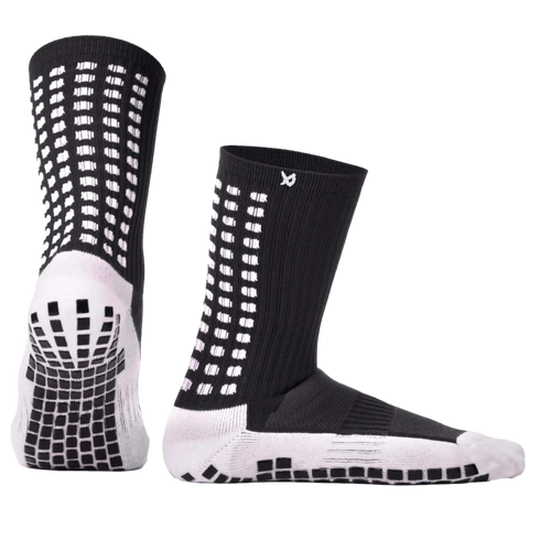 A pair of black and white crew socks with non-slip traction pads on the soles and white geometric designs on the ankles.