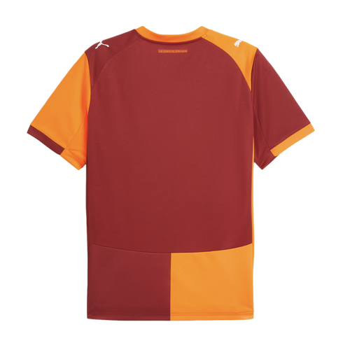 The back of a maroon and orange Puma football jersey with split-color panels and shoulder logos. A small Turkish phrase is printed below the orange collar.