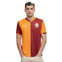 Man in an orange and maroon Galatasaray football jersey with a white Puma logo and team crest, standing against a black background with hands in pockets.