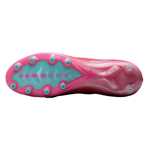 Underside of a pink and teal Nike soccer cleat featuring circular studs and "AIR ZOOM" branding on a light blue sole plate.