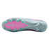 The underside of a light grey Nike soccer cleat, featuring a bright pink Air Zoom section and teal-colored conical studs.