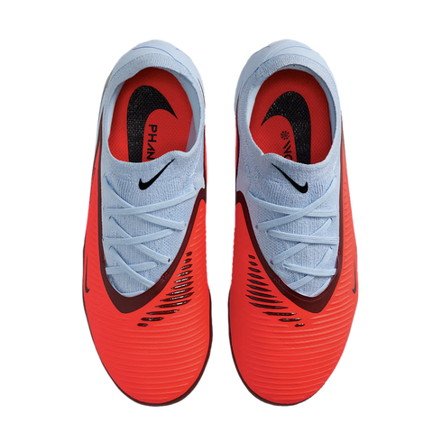 Top-down view of bright red and light blue Nike Phantom soccer cleats on a black background, featuring textured uppers and black swoosh logos.