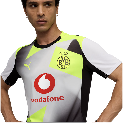 A man wearing a white, grey, and neon yellow Borussia Dortmund soccer jersey featuring a Vodafone sponsor logo, Puma branding, and geometric patterns.