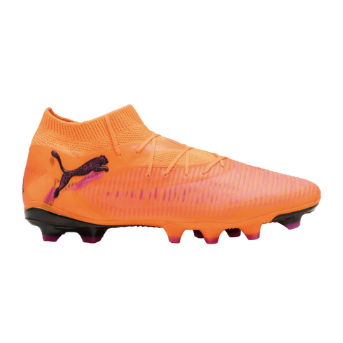 An orange Puma soccer cleat with a knitted collar, textured upper, and pink accents, shown in profile against a black background.