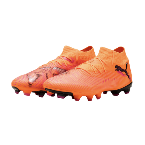 Vibrant orange Puma soccer cleats with pink and black accents, featuring a mid-cut collar and textured upper on a solid black background.