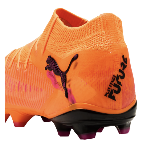 Bright orange Puma soccer cleat with a sock-like collar, black cat logo, and "PLAY FREE FUTURE" text on the heel, shown from a rear-quarter angle.
