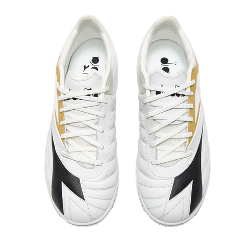 Top-down view of a pair of white Diadora sneakers with black and gold detailing and white laces, set against a solid black background.