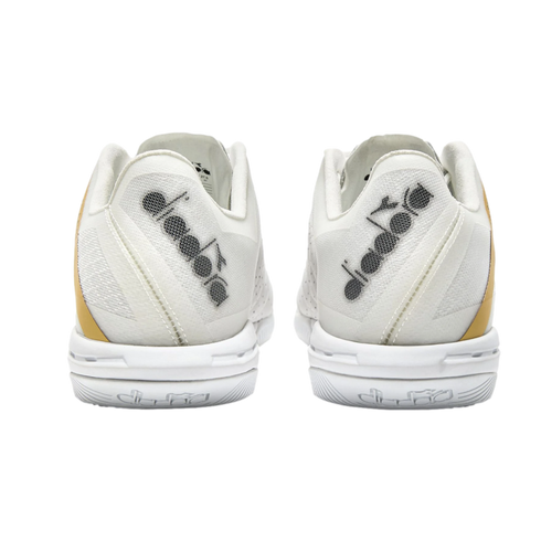 Rear view of a pair of white Diadora tennis shoes with gold side accents against a black background. The brand logo is featured on the mesh heels and white midsoles.