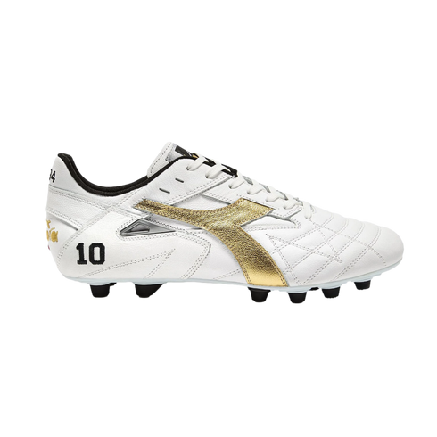 Profile of a white Diadora soccer cleat with a metallic gold logo and the number 10 on the heel. It has white laces and black studs, set against a solid black background.