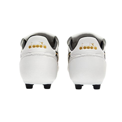 Rear view of white Diadora soccer cleats with gold logos on the heels, set against a solid black background.