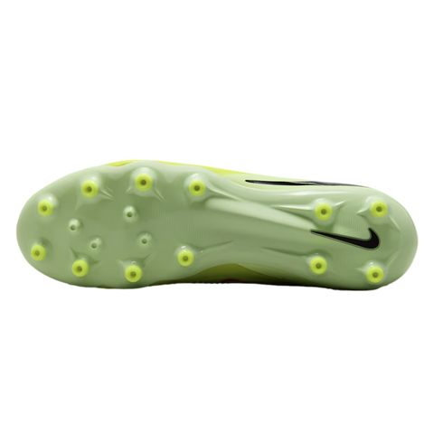 The light green soleplate of a Nike soccer cleat with yellow conical studs, shown against a black background.