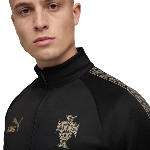 Man wearing a black Puma King track jacket with a gold Portugal national team crest and patterned shoulder detailing.