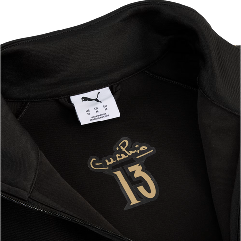 Inside of a black Puma jacket featuring a white size tag and a gold graphic with Eusébio's signature above the number 13.