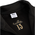 Inside of a black Puma jacket featuring a white size tag and a gold graphic with Eusébio's signature above the number 13.