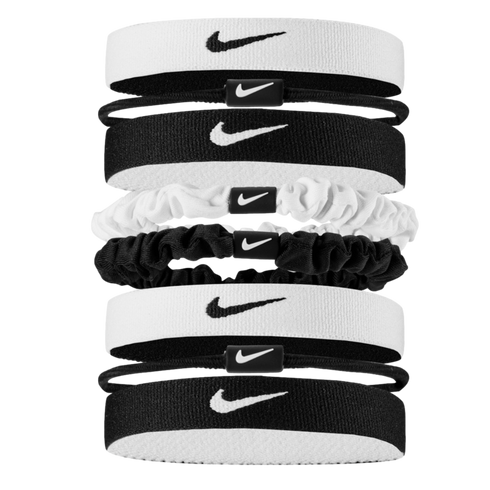 A vertical stack of eight black and white Nike hair accessories, including elastic headbands, thin hair ties, and scrunchies, all featuring the iconic swoosh logo against a black background.