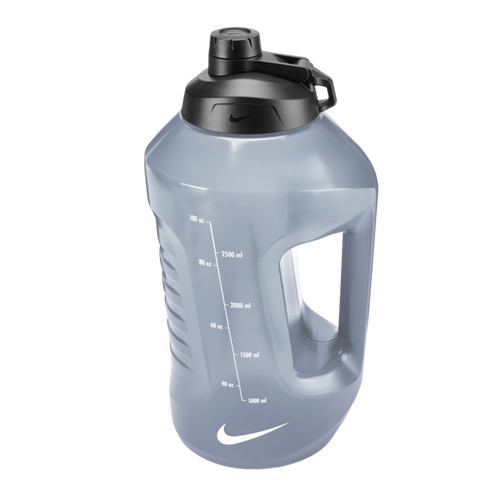 A grey semi-transparent Nike water jug with a black lid, integrated handle, and volume markings on the side.