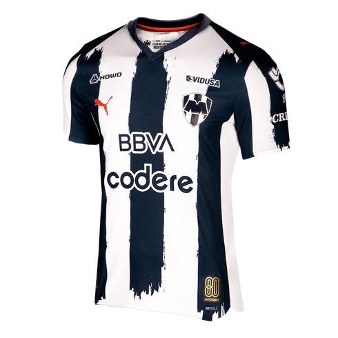 Puma Monterrey home soccer jersey featuring navy blue and white vertical brushstroke stripes, sponsor logos, and an 80th-anniversary gold patch.