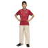 A boy posing in a red wavy-patterned sports jersey and cream-colored wide-leg trousers with his hands on his hips against a black background.