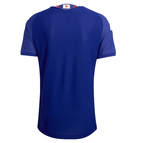 Back view of a blue short-sleeved soccer jersey featuring a small Japanese flag on the collar and a textured fabric pattern.