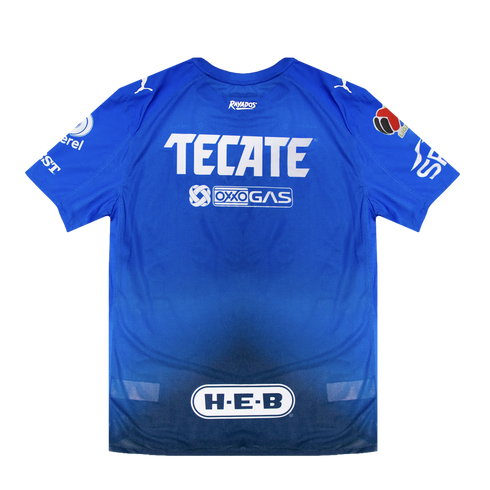 Back of a blue Rayados soccer jersey with white sponsor logos for Tecate, Oxxo Gas, and H-E-B against a black background.