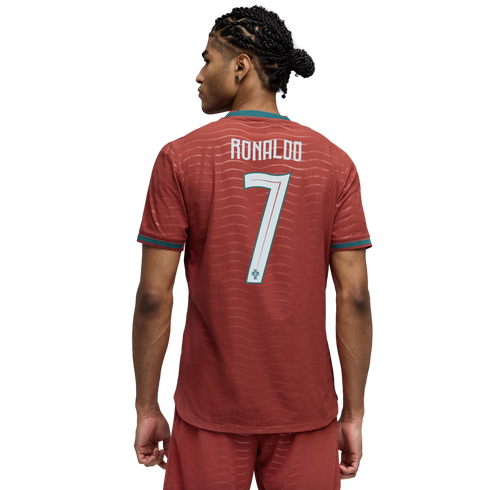 Back view of a man wearing a red Portugal jersey with "RONALDO" and "7" on the back. He has dark braided hair and is set against a black background.